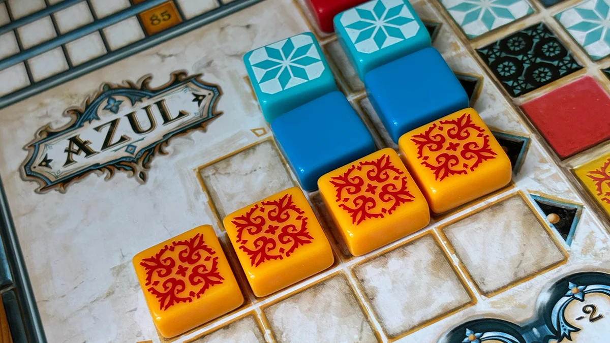 Close-up of an Azul board game player board showing a completed pattern line of yellow tiles ready to be scored onto the wall.